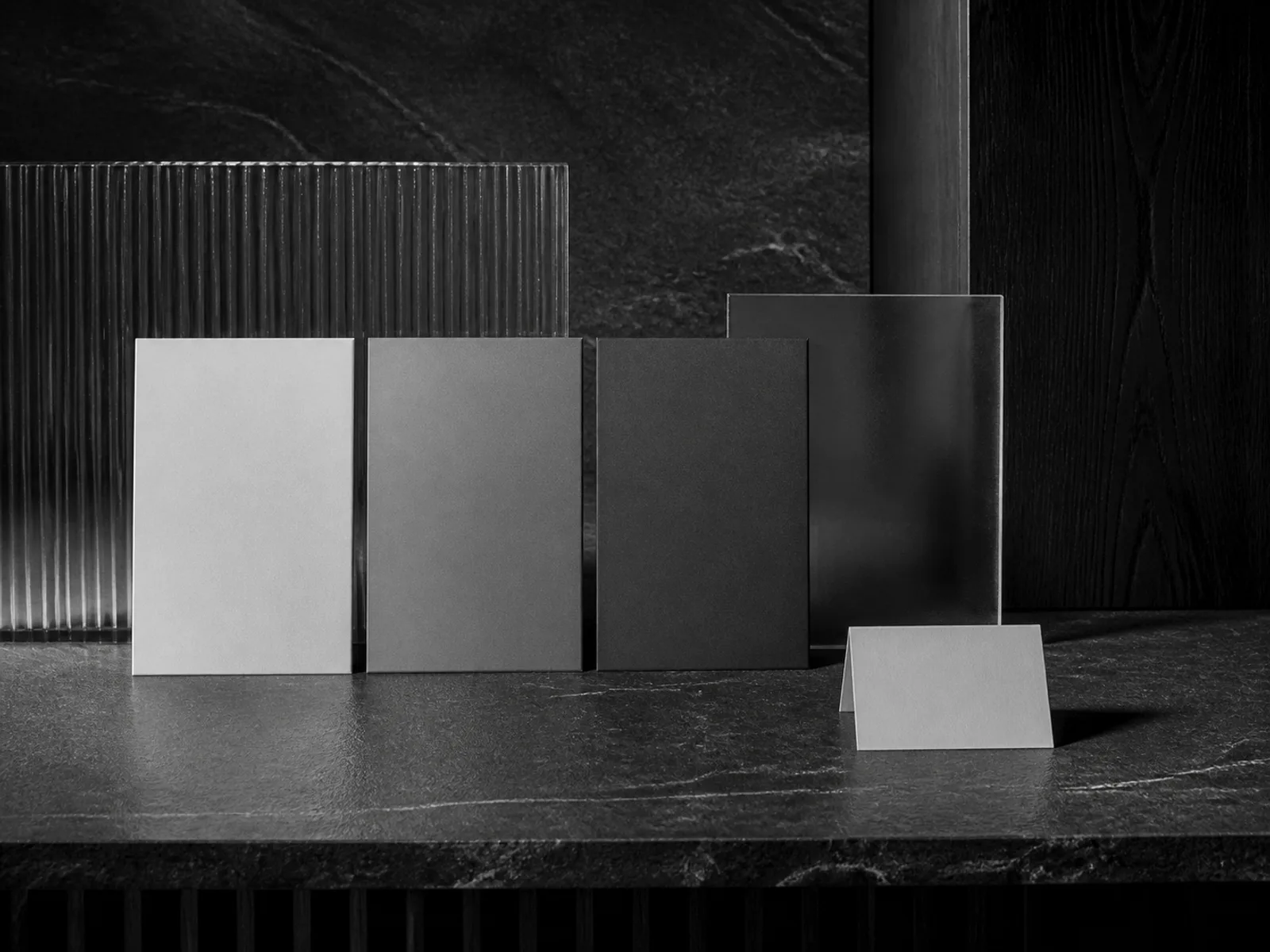 Placas fotográficas abstratas sem texto alinhadas sobre uma superfície escura em composição editorial preto e branco